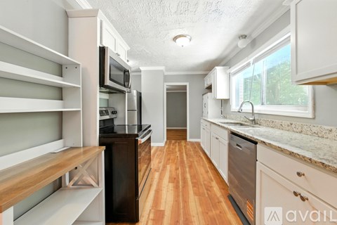 A kitchen with wooden floors and white cabinets.