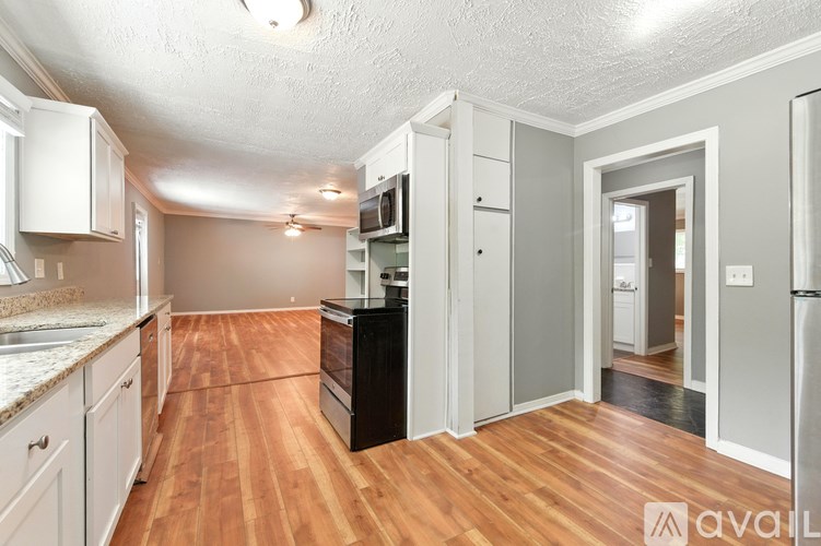 A kitchen with wooden floors and white cabinets.