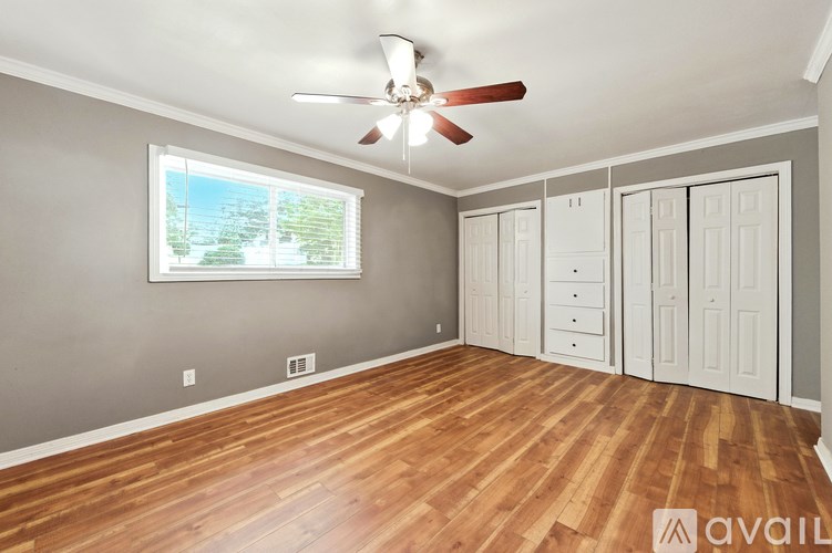 A room with a ceiling fan and wooden flooring.