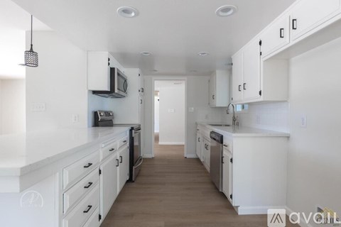 A kitchen with white cabinets and appliances.