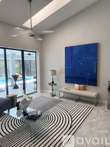 A living room with a black and white striped rug and a blue painting on the wall.