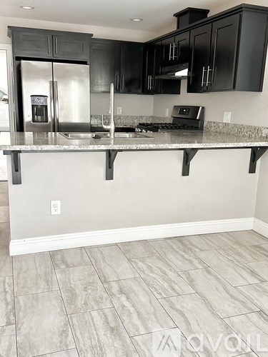 A kitchen with black cabinets and a marble countertop.