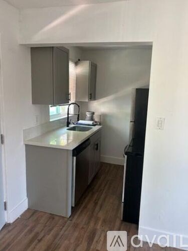 A kitchen with a white counter top and a black refrigerator.