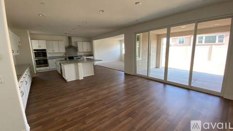 A spacious kitchen with white cabinets and a wooden floor.