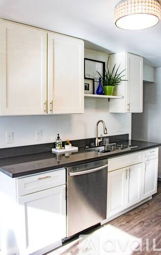 A kitchen with white cabinets and a black countertop.