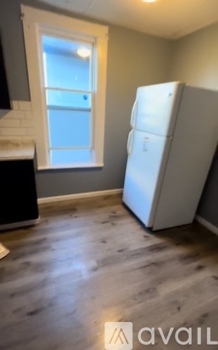 A white refrigerator in a kitchen with a window.