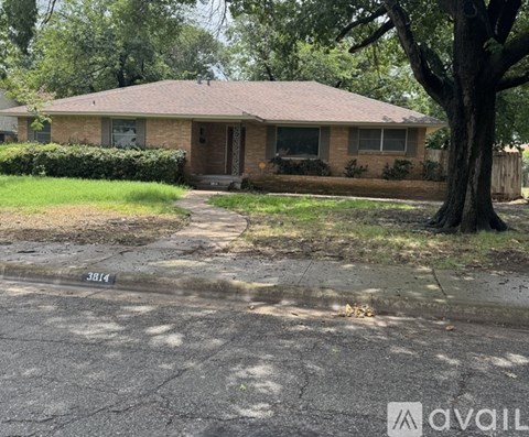 A house with a brown roof and a tree in front of it.