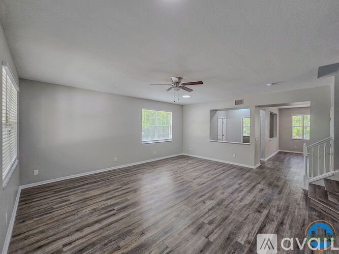 A spacious room with wooden flooring and a ceiling fan.