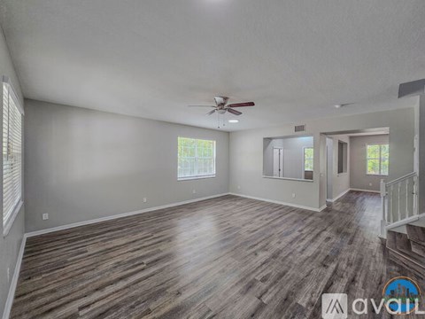 A spacious room with wooden flooring and a ceiling fan.