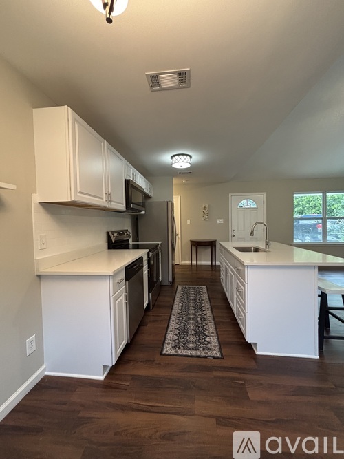 A well-lit kitchen with white cabinets and a dining area.