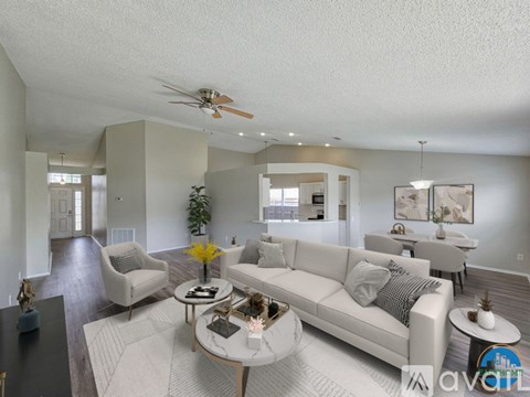 A spacious living room with a white sofa set and a coffee table.