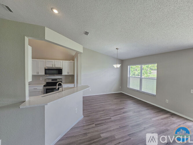 A kitchen with white cabinets and a countertop is visible from the living room.