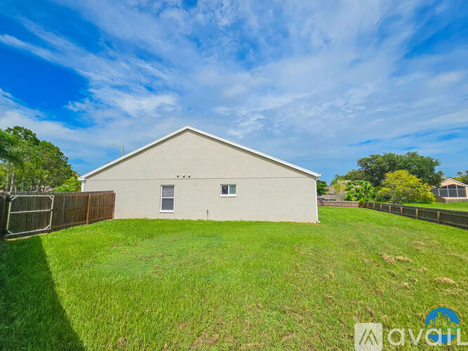 A white barn-like building with a fence in front of it.