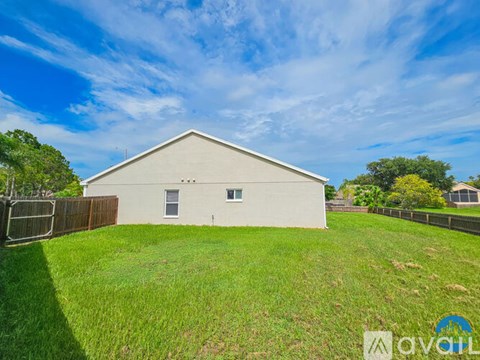 A white barn-like building with a fence in front of it.