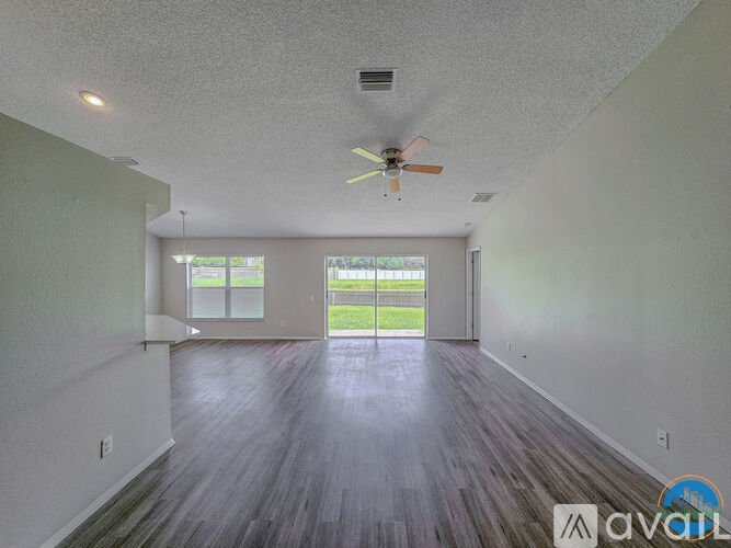 A spacious room with a ceiling fan and sliding glass doors leading to a green outdoor area.