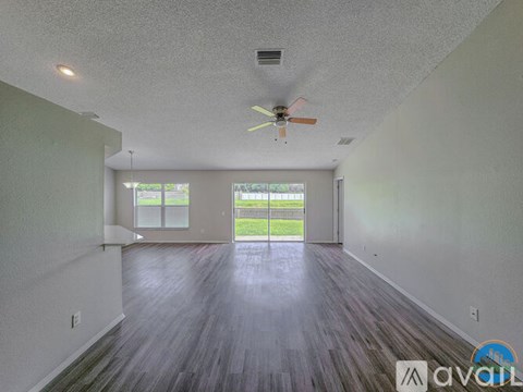 A spacious room with a ceiling fan and sliding glass doors leading to a green outdoor area.
