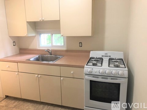 A kitchen with a white stove and cabinets.