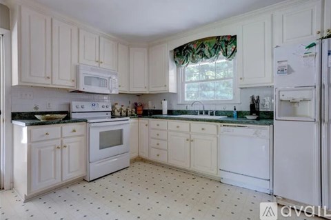 A kitchen with white cabinets and a black and white floor.