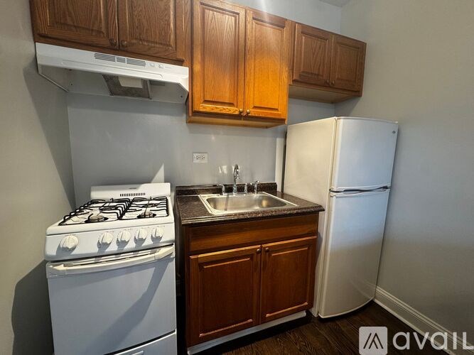A kitchen with a white gas stove, a white refrigerator, and wooden cabinets.