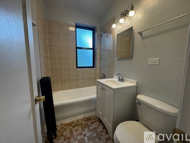A bathroom with a tub, toilet, sink, and window.