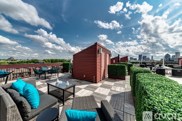 A rooftop patio with a table, chairs, and a red shed.