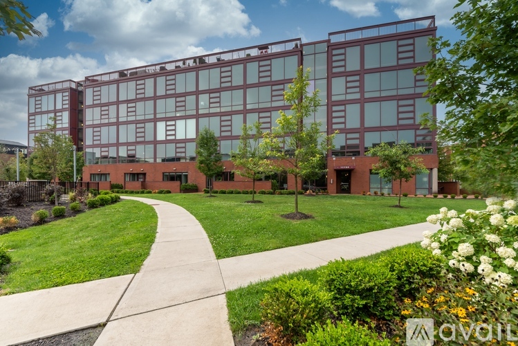 A modern building with a glass facade is surrounded by a well-manicured lawn and a walking path.