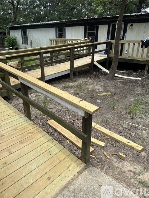 A wooden deck with a railing is in front of a white building.