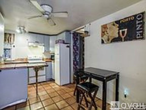 A kitchen with a refrigerator, table and chairs.