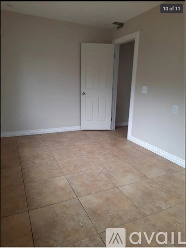 A room with a white door and tiled floor.