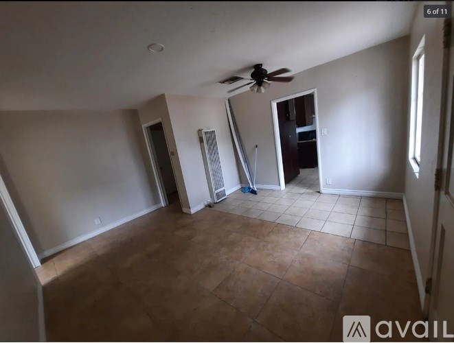 A room with a ceiling fan and a door leading to another room.