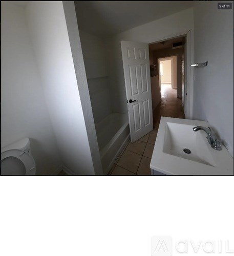 A white bathroom with a toilet, sink and door.