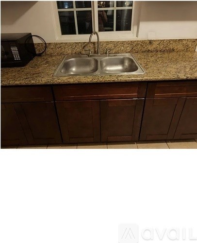 A kitchen with a sink and a microwave on the counter.