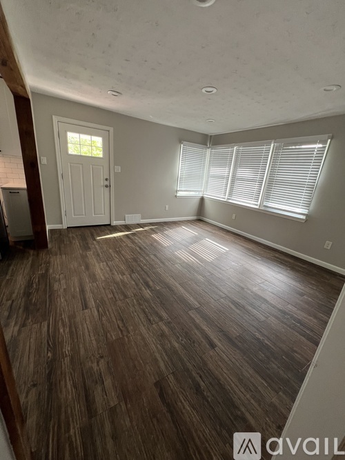 A room with wooden flooring and a white door.