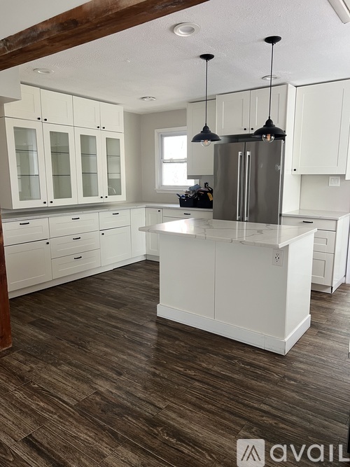 A kitchen with white cabinets and a wooden floor.