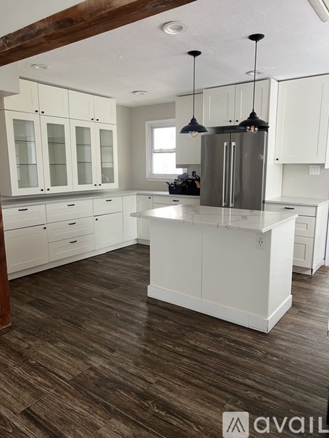 A kitchen with white cabinets and a wooden floor.