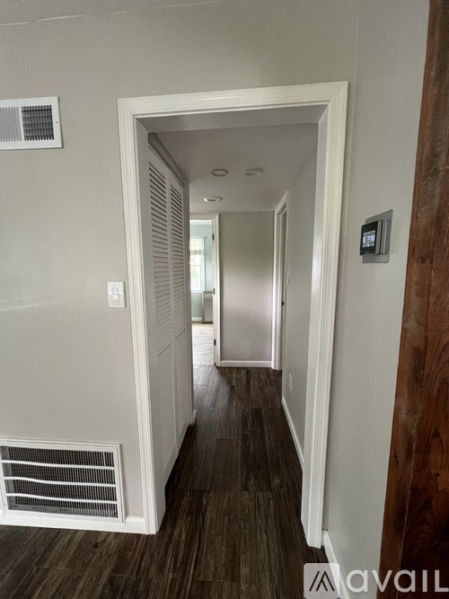 A hallway with a white door and a wall-mounted thermostat.