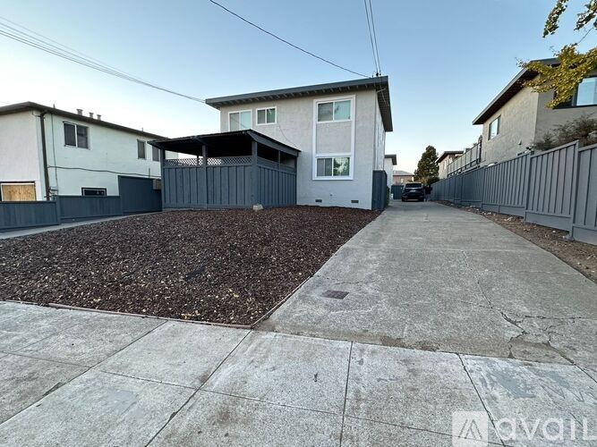 A house with a grey fence and a driveway in front.