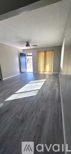 A room with a ceiling fan and a door leading to a hallway.