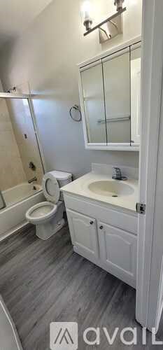 A white bathroom with a toilet, sink, and shower.