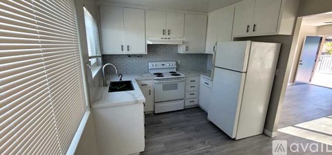 A kitchen with white appliances and cabinets.