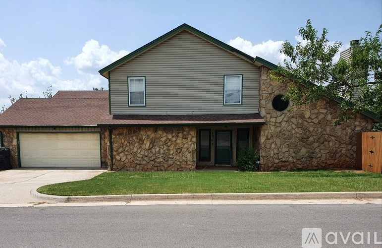 A house with a stone wall and a brown roof.