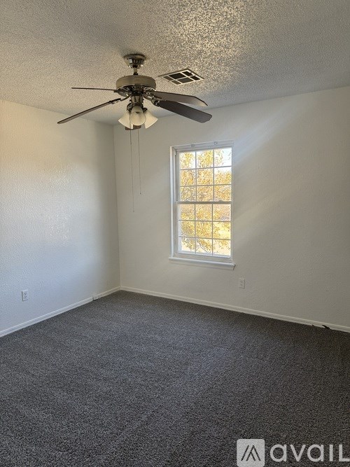 A room with a ceiling fan and a window.