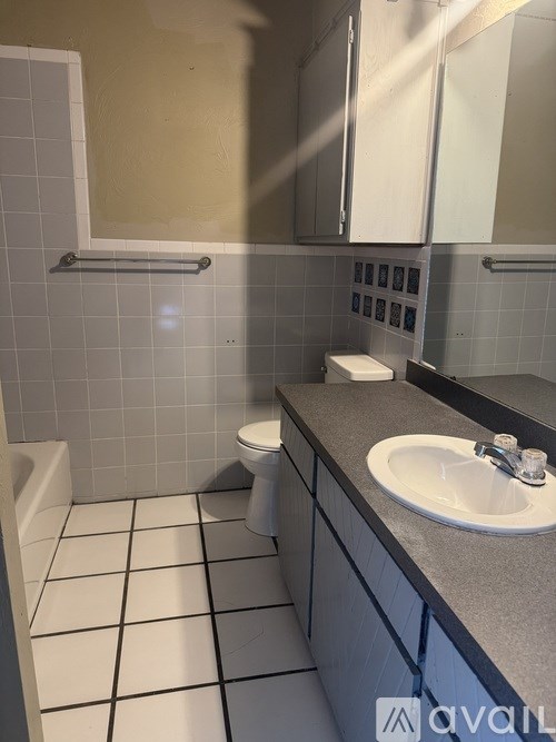 A bathroom with a toilet, sink, and mirror.