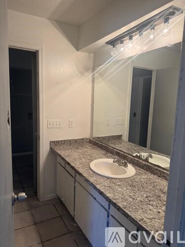 A bathroom with granite countertops and a white sink.