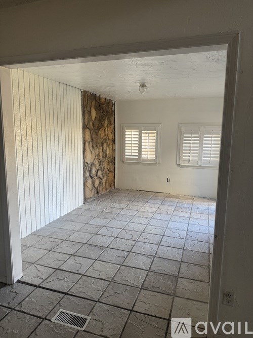 A room with a tiled floor and a window with blinds.