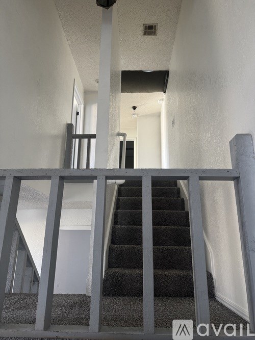 A staircase with a metal railing and a black carpet.