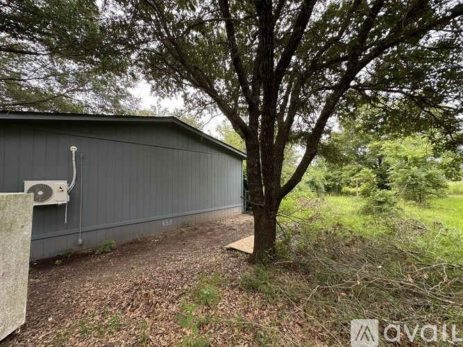 A grey building with a tree in front of it.