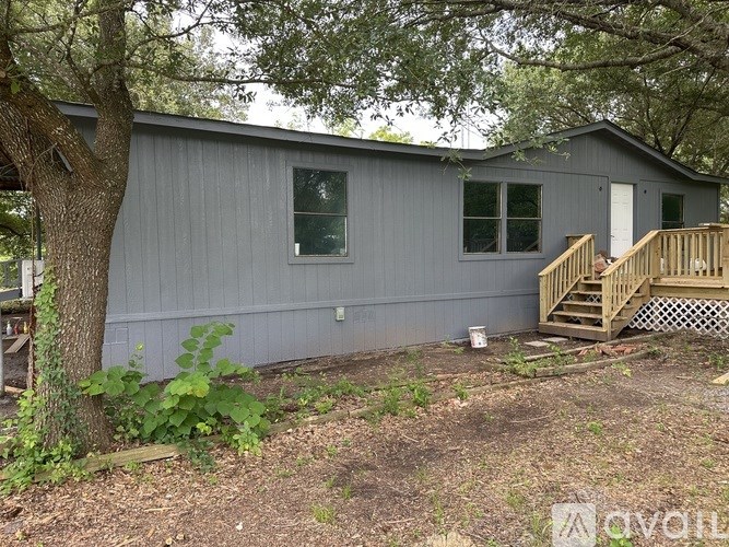 A grey house with a wooden staircase leading to the door.