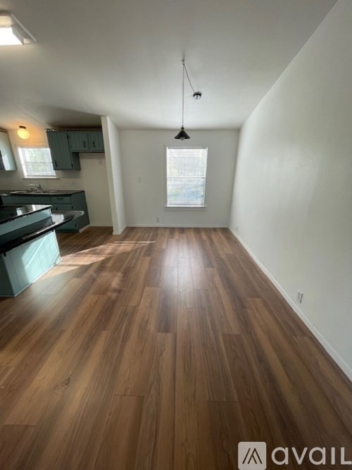 A room with wooden flooring and a window with blinds.