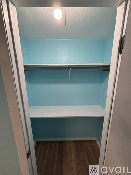 A small closet with a white shelf and a light on.